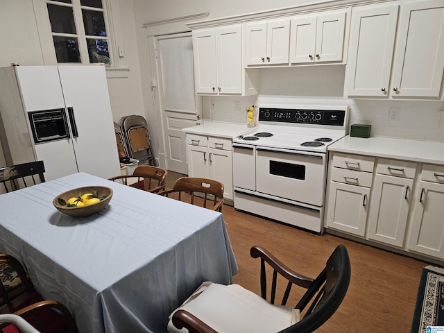 kitchen featuring tasteful backsplash, white appliances, dark hardwood / wood-style floors, and white cabinets