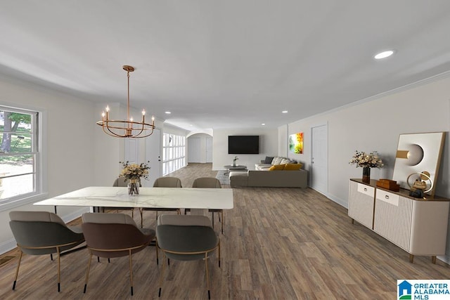 dining area featuring hardwood / wood-style flooring, ornamental molding, a healthy amount of sunlight, and a notable chandelier