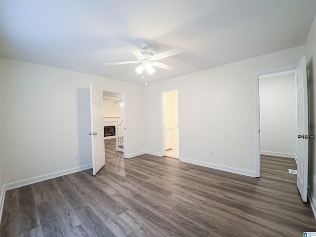 unfurnished bedroom with a walk in closet, dark hardwood / wood-style floors, ceiling fan, and ensuite bathroom