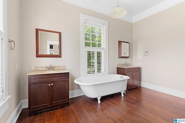 bathroom with hardwood / wood-style flooring, ornamental molding, a bathing tub, and vanity