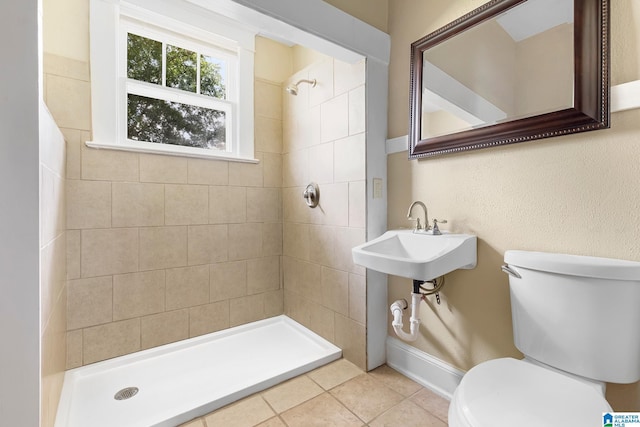 bathroom with tile patterned floors, toilet, sink, and a tile shower