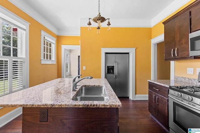 kitchen with sink, hanging light fixtures, stainless steel appliances, dark brown cabinetry, and an island with sink