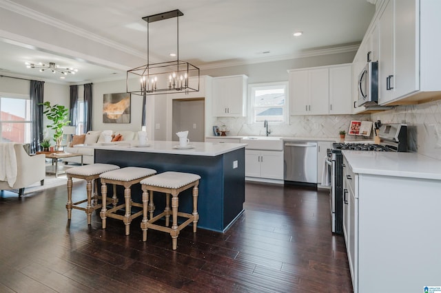 kitchen featuring a kitchen island, appliances with stainless steel finishes, pendant lighting, white cabinets, and decorative backsplash