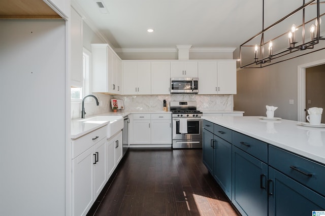 kitchen with pendant lighting, sink, white cabinetry, stainless steel appliances, and blue cabinets