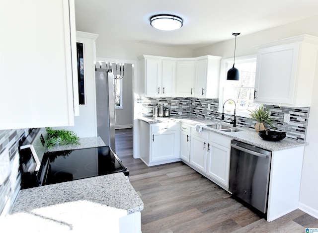 kitchen featuring pendant lighting, white cabinetry, sink, stainless steel appliances, and light stone countertops