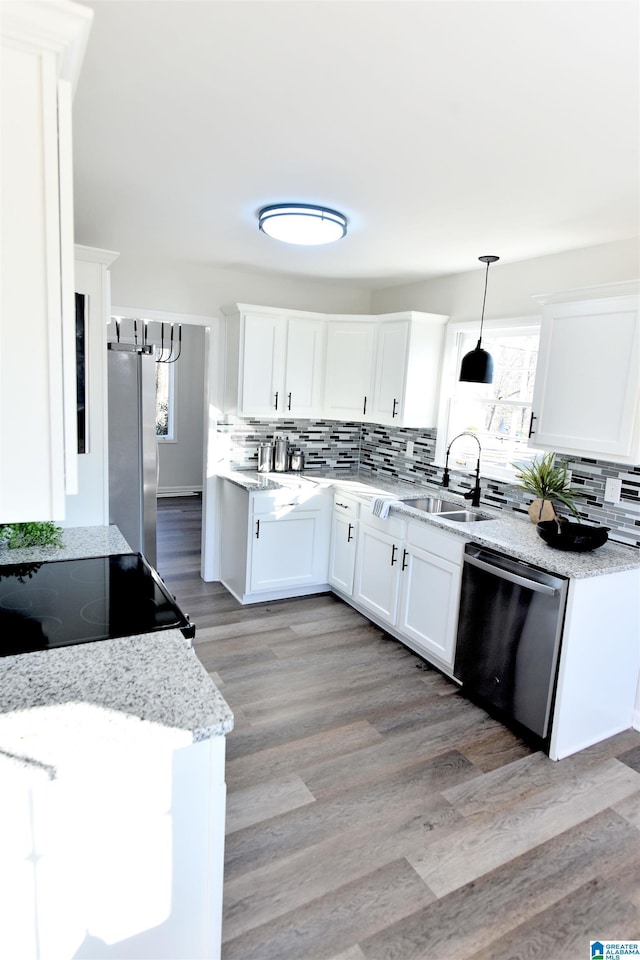 kitchen featuring appliances with stainless steel finishes, sink, white cabinets, and decorative light fixtures