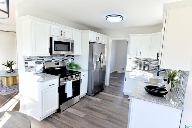 kitchen featuring stainless steel appliances, light wood-type flooring, white cabinets, and light stone counters