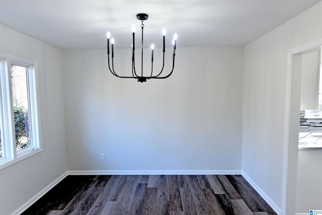 unfurnished dining area with a notable chandelier and dark wood-type flooring