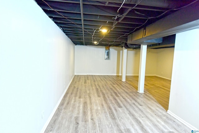 basement with electric panel and light hardwood / wood-style flooring