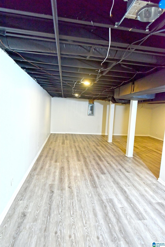 basement with hardwood / wood-style flooring and electric panel