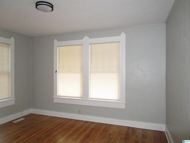 spare room featuring ornamental molding and dark hardwood / wood-style floors