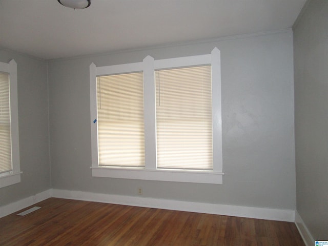 empty room featuring dark wood-type flooring and ornamental molding