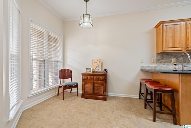 interior space featuring sink, crown molding, a breakfast bar, backsplash, and decorative light fixtures