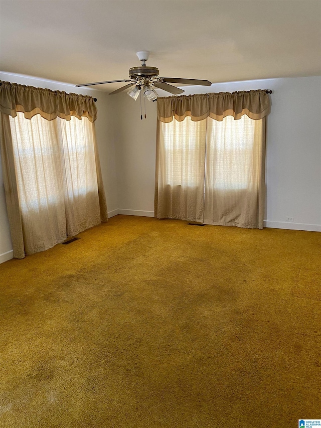 carpeted spare room featuring ceiling fan and a healthy amount of sunlight