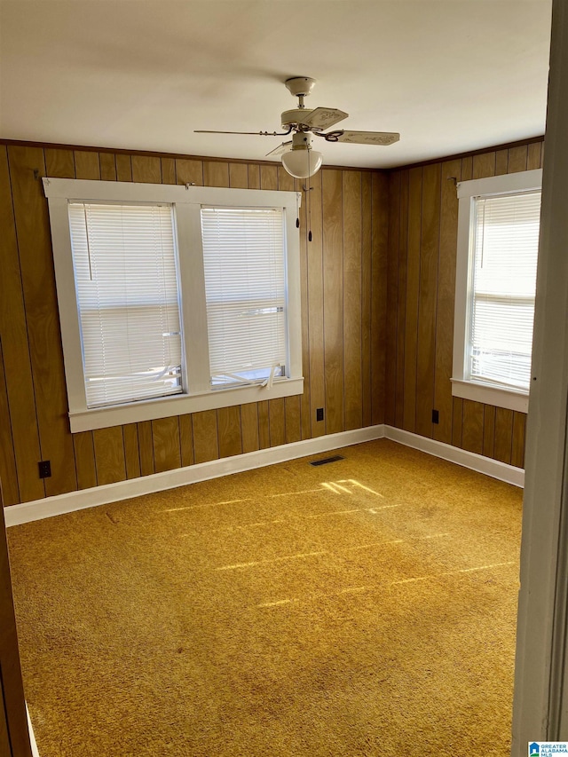 unfurnished room featuring ceiling fan, carpet, and wooden walls