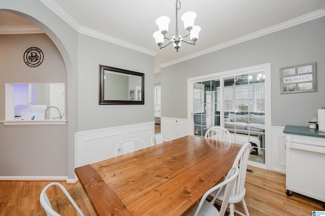 dining area featuring ornamental molding, a chandelier, and light hardwood / wood-style flooring