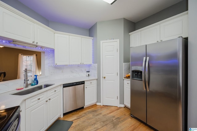 kitchen with sink, white cabinetry, tasteful backsplash, light wood-type flooring, and appliances with stainless steel finishes