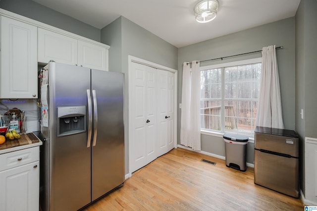 kitchen with white cabinets, stainless steel refrigerator, stainless steel fridge, and light wood-type flooring