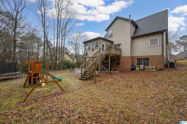 rear view of house with a trampoline, central AC unit, a playground, and a deck