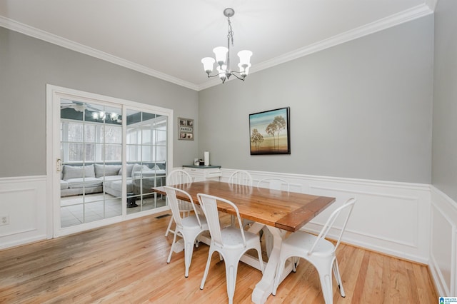 dining area featuring crown molding, light hardwood / wood-style floors, and a chandelier