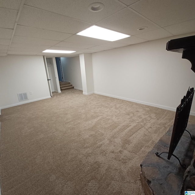 basement with a paneled ceiling and carpet