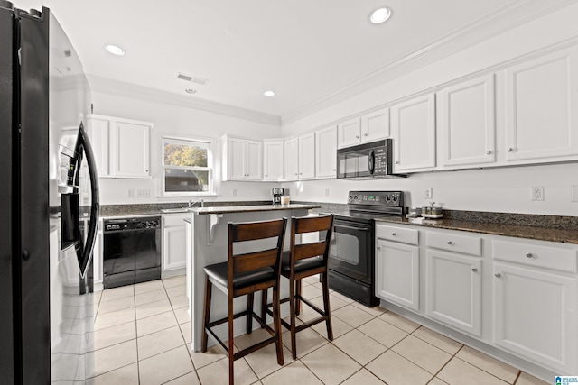 kitchen featuring light tile patterned floors, a breakfast bar area, ornamental molding, black appliances, and white cabinets