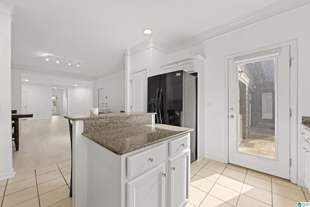 kitchen featuring white cabinetry, dark stone counters, crown molding, and light tile patterned floors