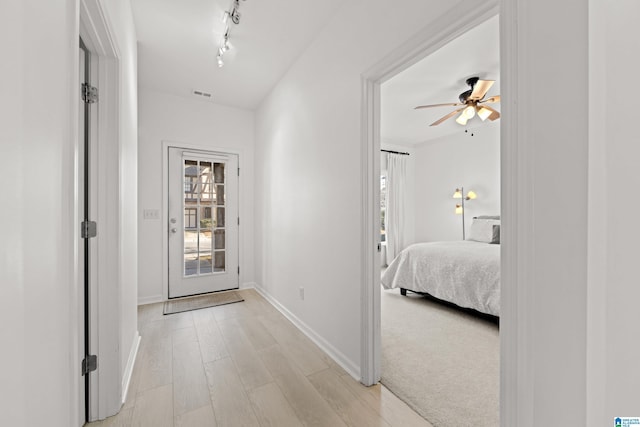 hallway with rail lighting and light wood-type flooring