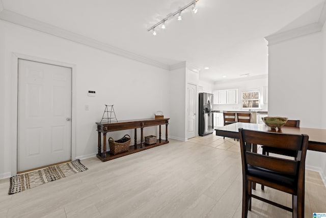 dining room with rail lighting, ornamental molding, and light hardwood / wood-style floors