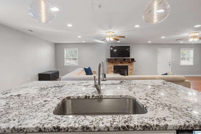 kitchen featuring a healthy amount of sunlight, light stone countertops, sink, and ceiling fan