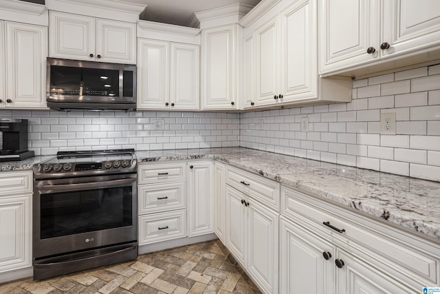 kitchen featuring white cabinetry, appliances with stainless steel finishes, light stone counters, and decorative backsplash