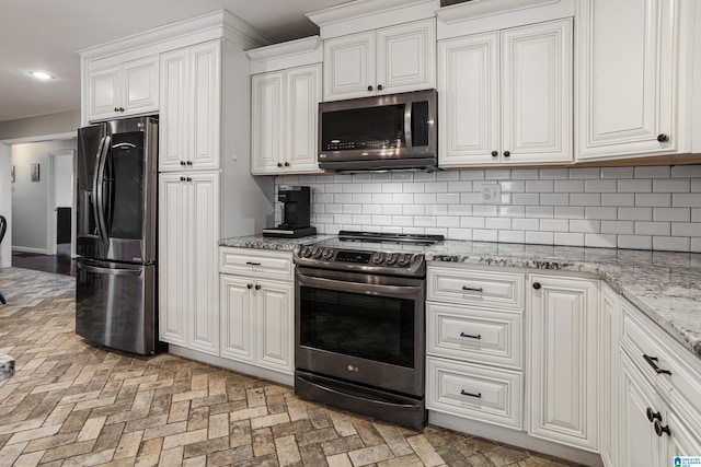 kitchen with white cabinetry, backsplash, light stone counters, and appliances with stainless steel finishes