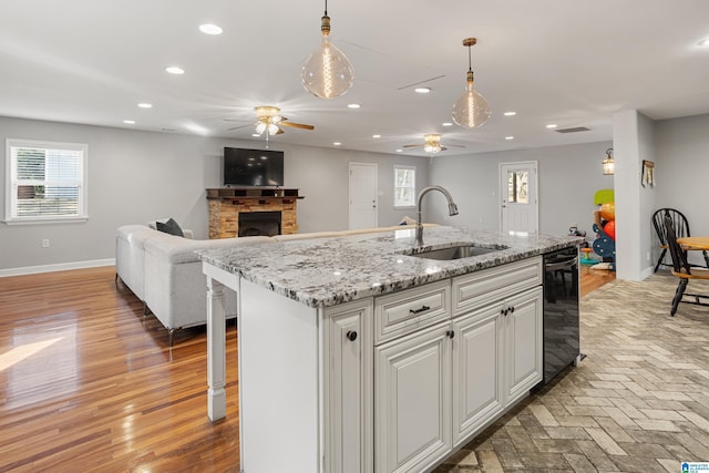 kitchen featuring decorative light fixtures, an island with sink, sink, white cabinets, and a kitchen breakfast bar