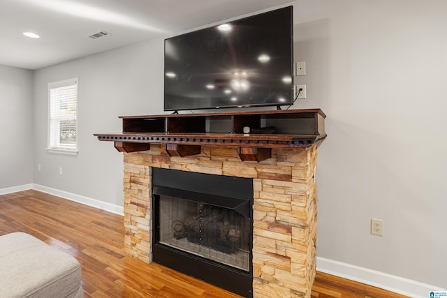 room details with a stone fireplace and hardwood / wood-style floors