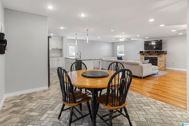 dining room featuring ceiling fan, sink, and light wood-type flooring