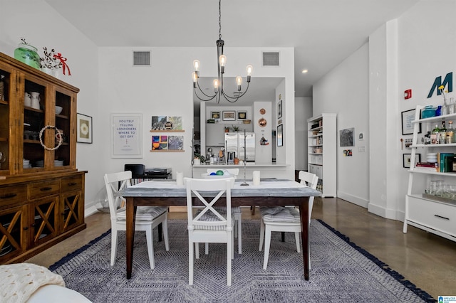 dining area featuring a notable chandelier and concrete floors