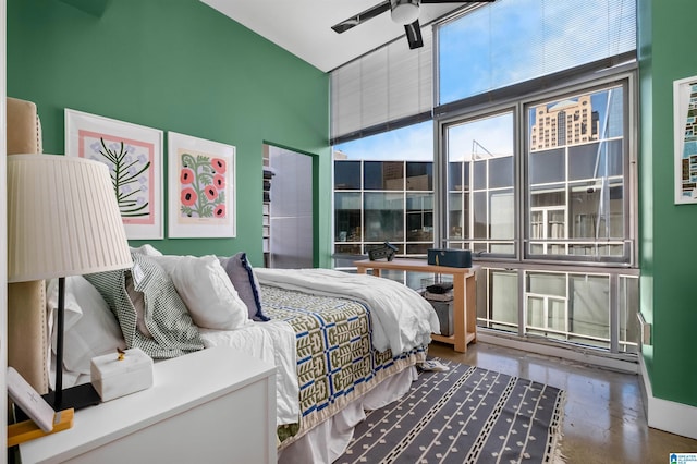 bedroom featuring ceiling fan, a wall of windows, and concrete floors