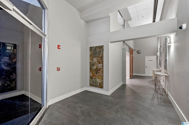 hall featuring a barn door and a high ceiling