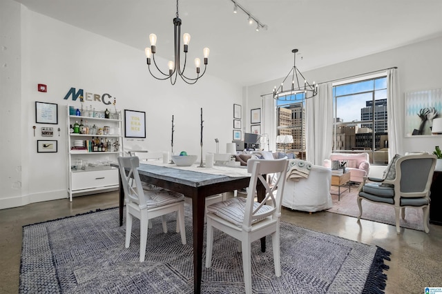 dining area featuring an inviting chandelier, rail lighting, and concrete floors