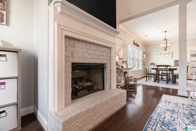 living room with a fireplace, crown molding, dark wood-type flooring, and a notable chandelier