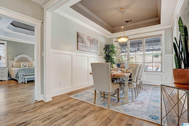 dining area featuring hardwood / wood-style flooring, crown molding, and a raised ceiling