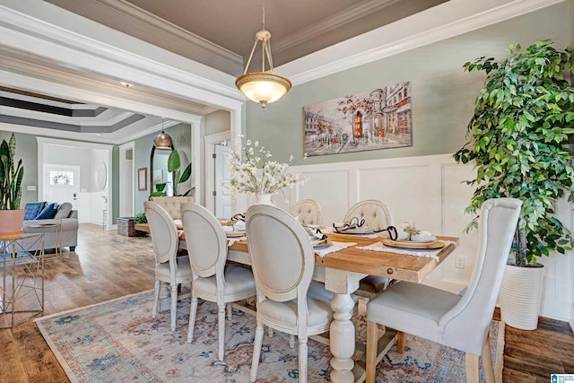 dining area featuring dark hardwood / wood-style floors, ornamental molding, and a raised ceiling