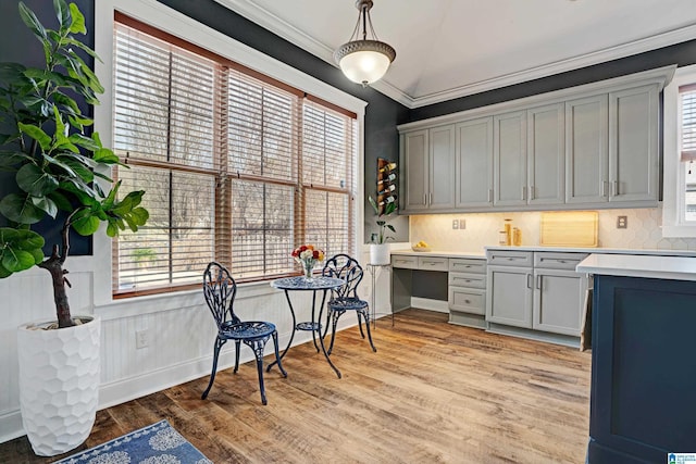 kitchen with light hardwood / wood-style flooring, crown molding, gray cabinets, and decorative backsplash