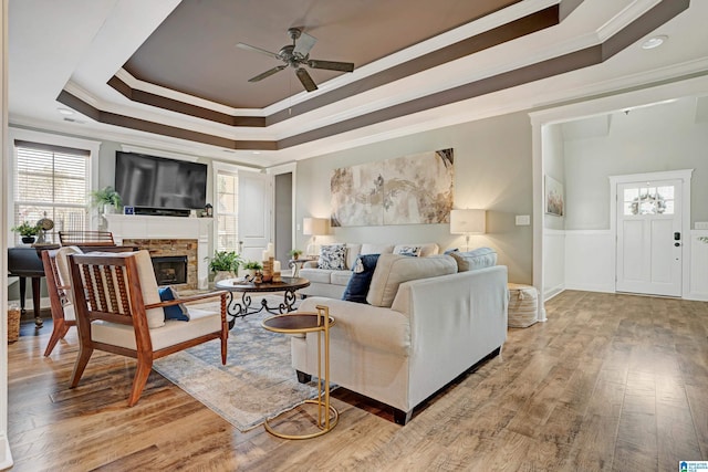 living room featuring a raised ceiling, crown molding, hardwood / wood-style floors, and a fireplace