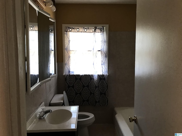 bathroom featuring vanity, a bath, tile walls, and toilet