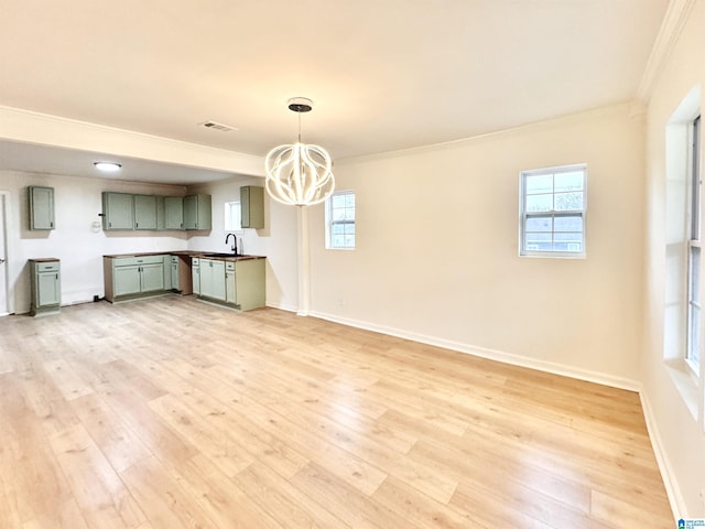 kitchen featuring sink, crown molding, light wood-type flooring, green cabinets, and pendant lighting