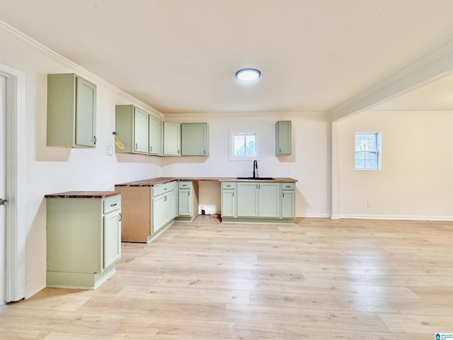 kitchen with sink, crown molding, light hardwood / wood-style flooring, and green cabinets