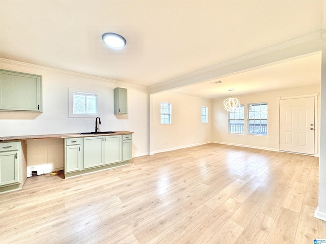 kitchen featuring sink, green cabinets, plenty of natural light, light hardwood / wood-style floors, and decorative light fixtures