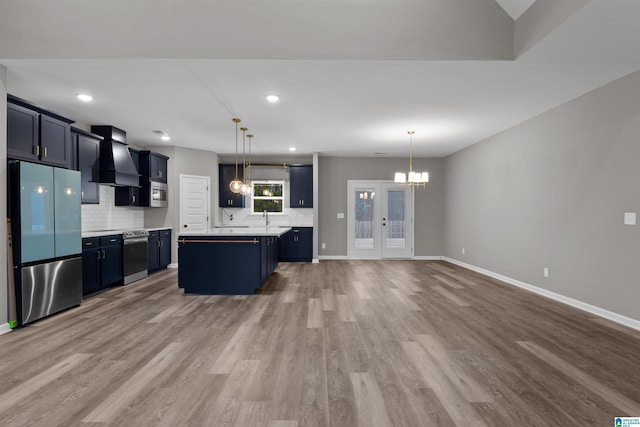 kitchen with pendant lighting, stainless steel appliances, a kitchen island, and custom range hood