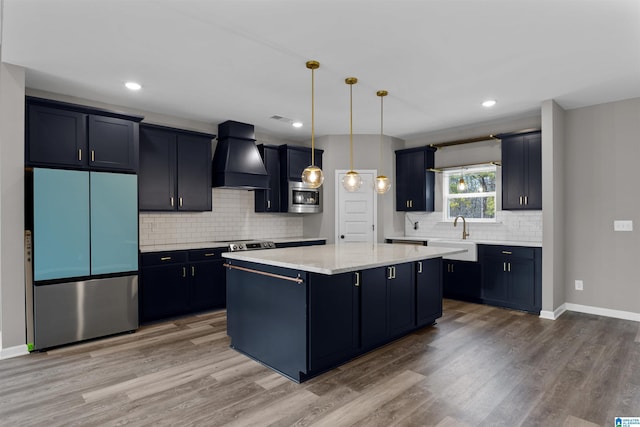 kitchen featuring premium range hood, hanging light fixtures, fridge, a center island, and stainless steel microwave